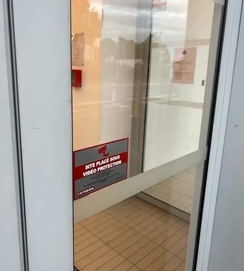 Porte vitrée portant l'affichage « site placé sous vidéoprotection », posé à l'entrée d'une zone filmée