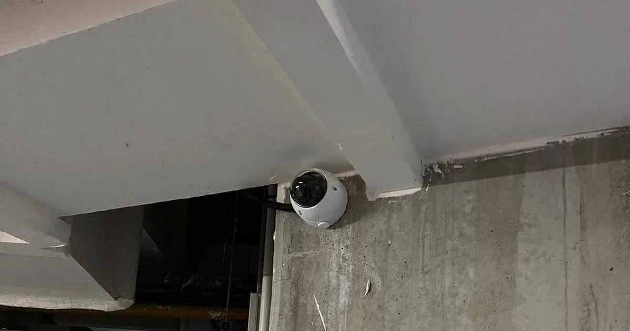 Caméra dôme au plafond d'un parking souterrain, près d'une issue de secours