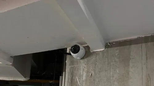 Caméra dôme au plafond d'un parking souterrain, près d'une issue de secours