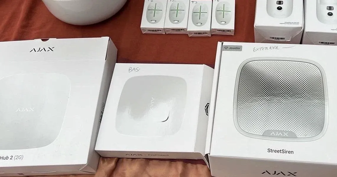 Générateur de brouillard anti-intrusion blanc fixé au mur d'une réserve de magasin, avec une recharge de fluide posée sur une étagère