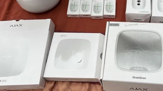 Générateur de brouillard anti-intrusion blanc fixé au mur d'une réserve de magasin, avec une recharge de fluide posée sur une étagère