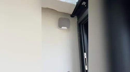Sirène d'alarme Ajax blanche posée en façade, à côté d'une porte-fenêtre