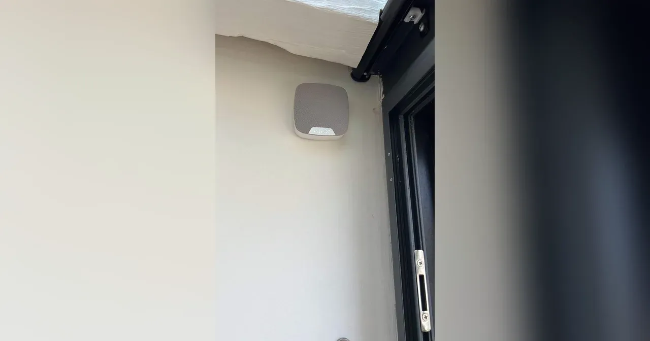 Sirène d'alarme Ajax blanche posée en façade, à côté d'une porte-fenêtre