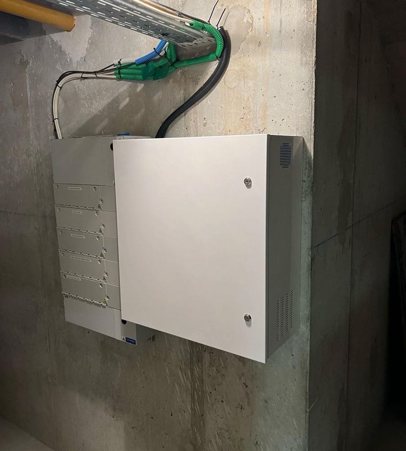 Armoire technique posée sur un mur en béton, câbles arrivant par le haut