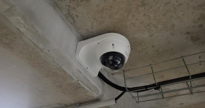 Caméra dôme sur un plafond en béton, à côté d'un chemin de câbles