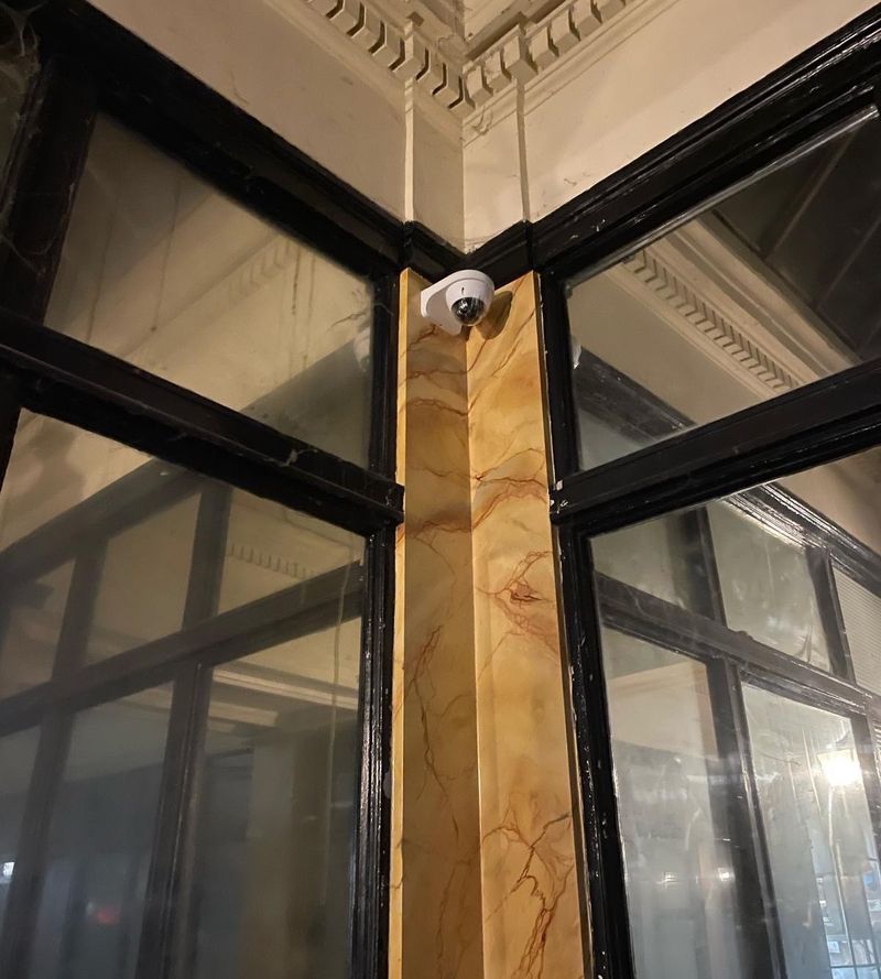 Caméra dôme fixée dans l'angle d'un hall d'immeuble ancien, sous les moulures