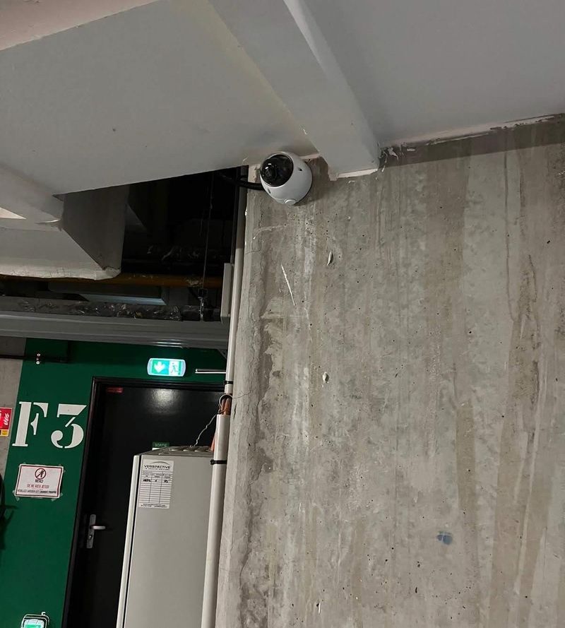 Caméra dôme au plafond d'un parking souterrain, près d'une issue de secours